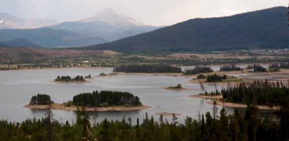 [Numerous small islands each crowded with evergreens sit in a lake surrounded by mountains.]